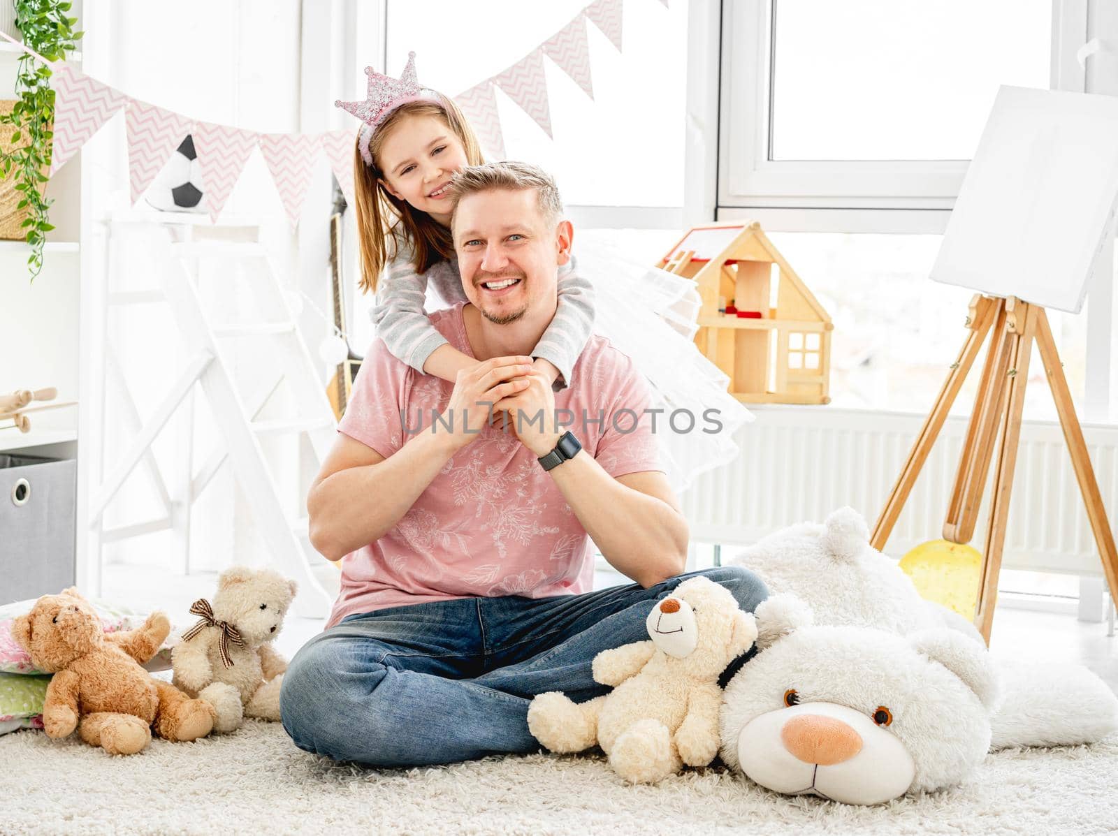 Happy father hugging beautiful little daughter in playroom