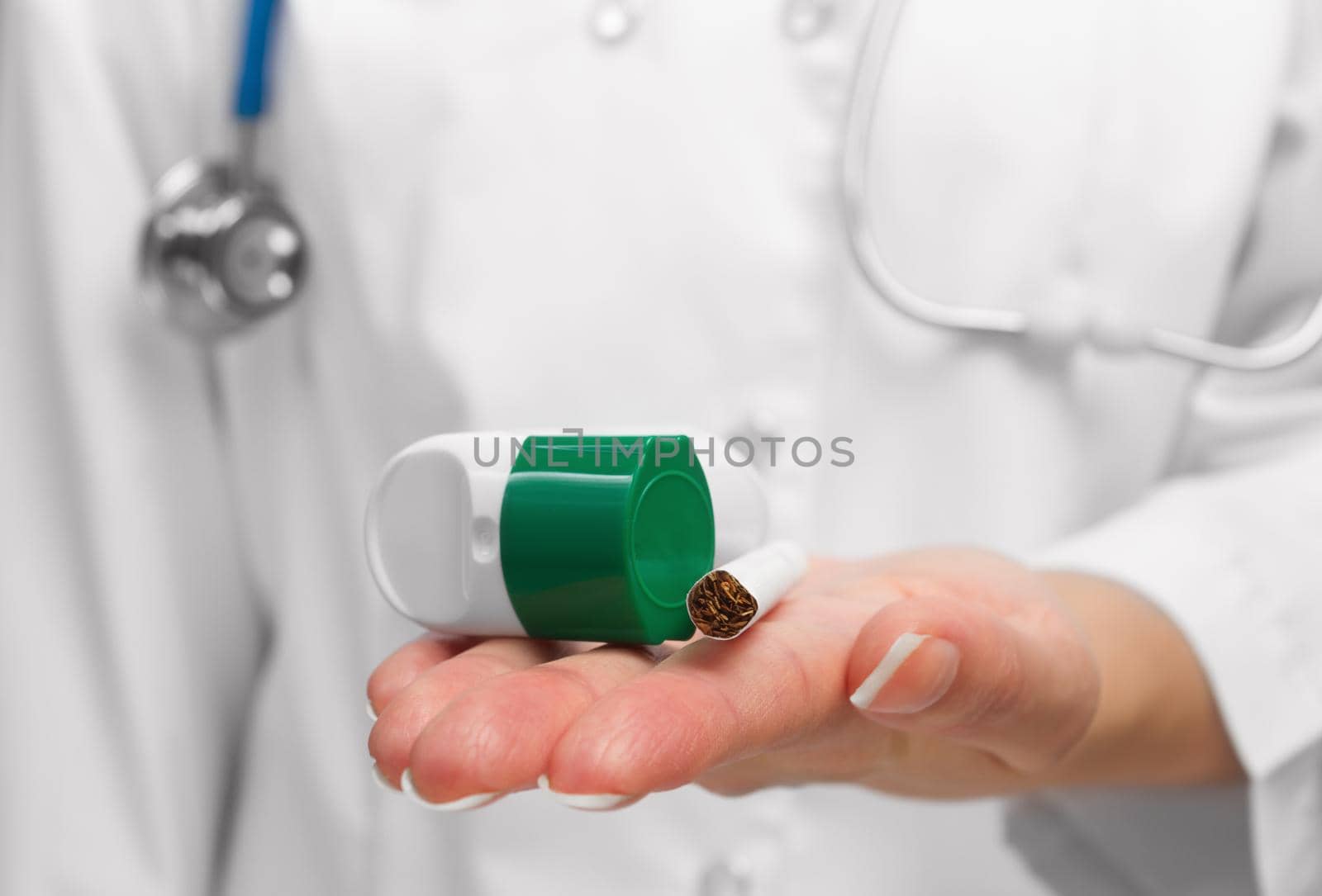 Doctor shows the result of a long smoking: an inhaler near a cigarette