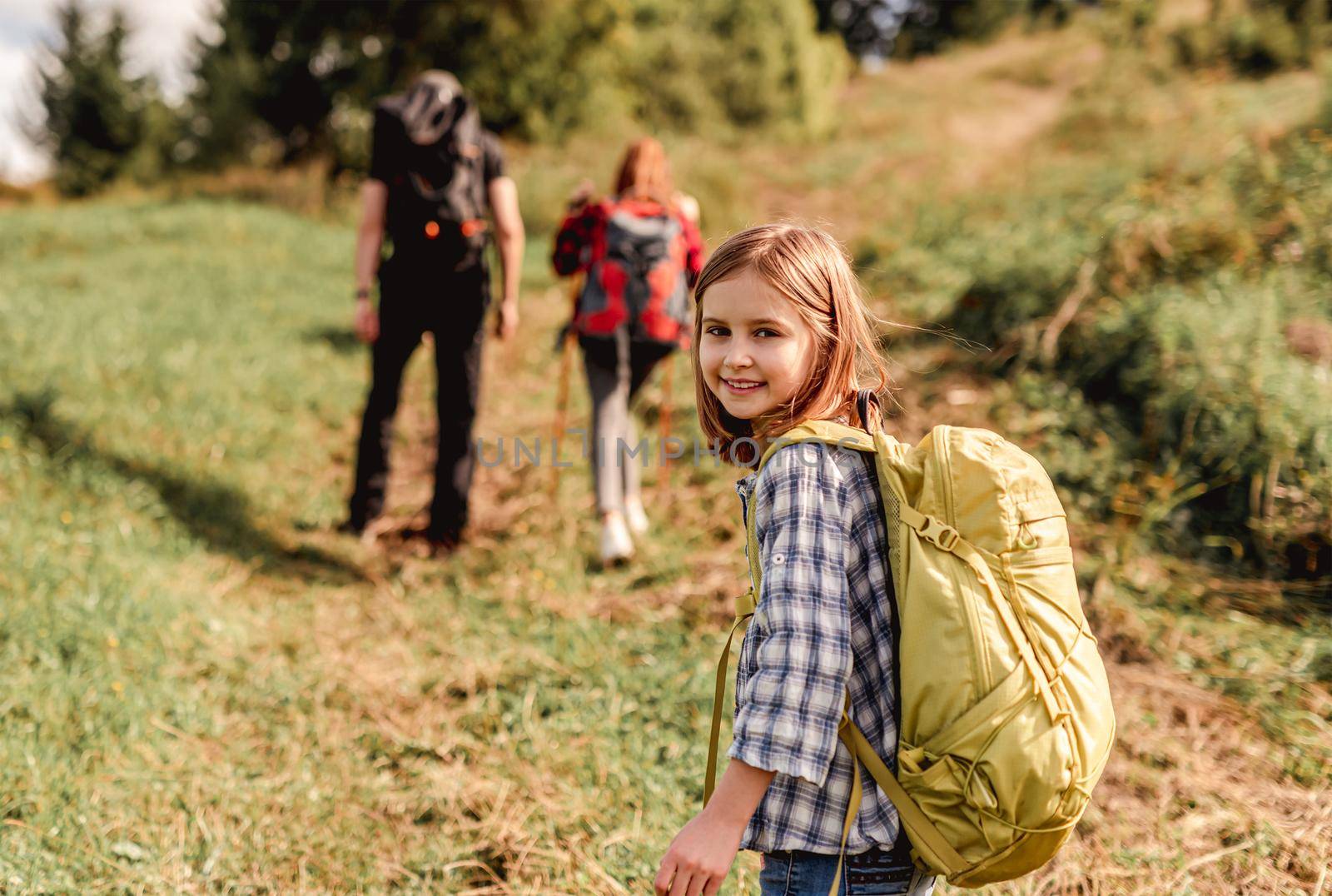 Smiling little girl trekking in mountains with family