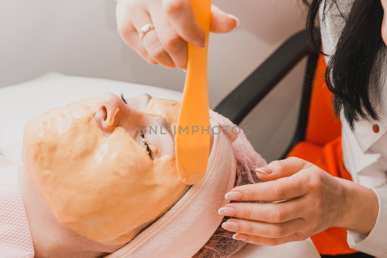 Woman at the beautician applying a relaxing golden mask on the face, restoring and moisturizing the skin. new