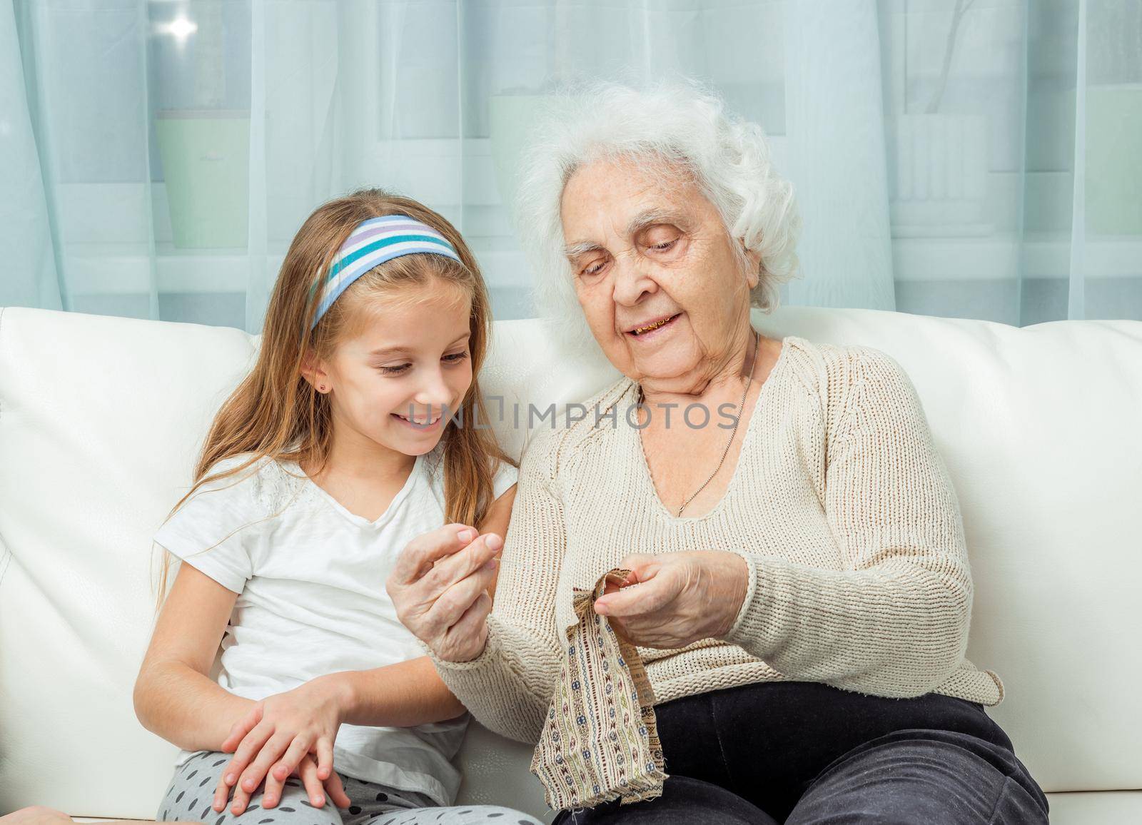 ganddaughter learning to embroider with granny on sofa