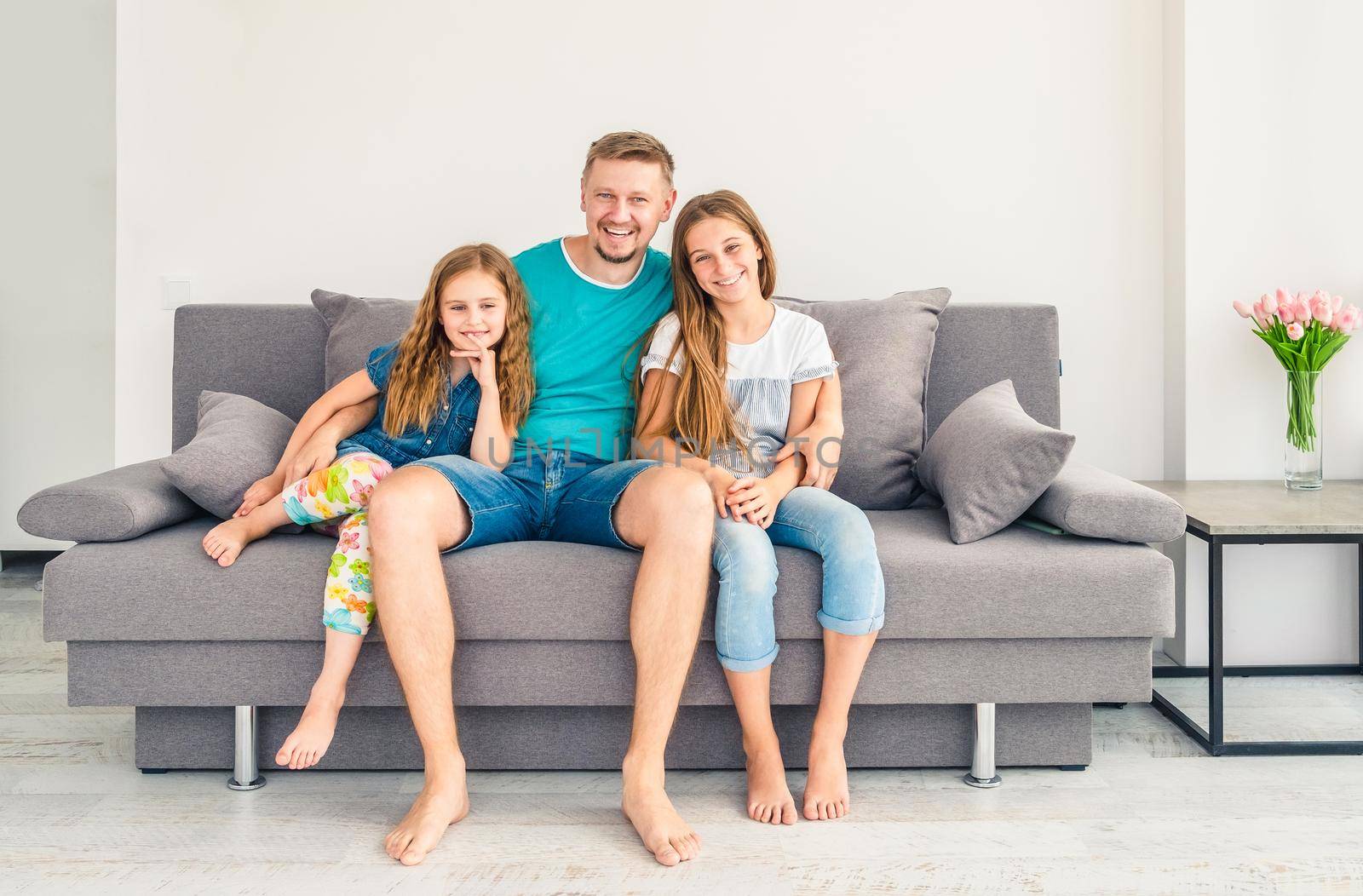 Portrait of happy father with two adorable smiling daughters on the couch