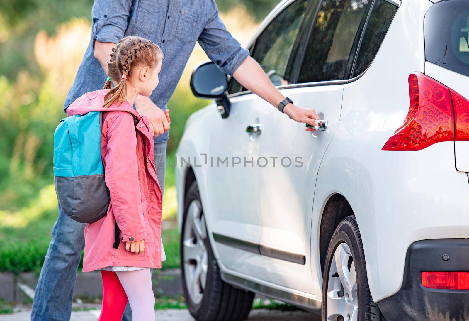 Father meeting daughter after school and opening back car door