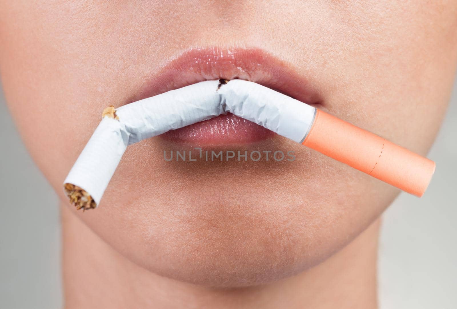 Female lips holding a broken cigarette, close-up
