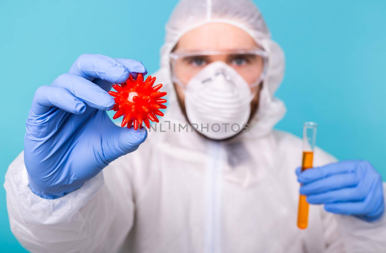 Covid-19, Vaccine development and medicine concept - Man scientist dressed personal protective equipment and holding a model of coronavirus and test tube. by Satura86
