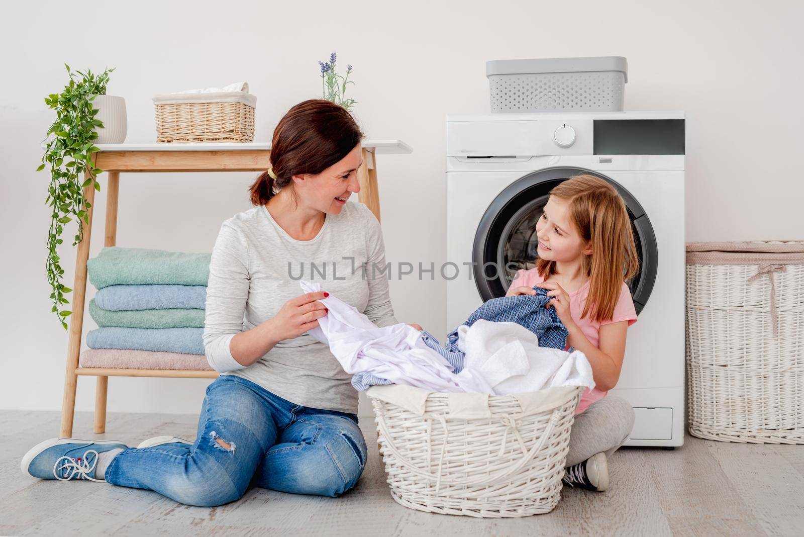 Mother with daughter sorting clothes after laundry by tan4ikk1