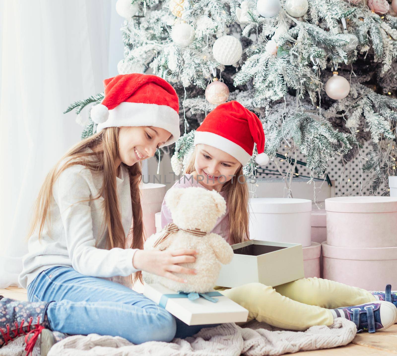 Smiling sisters in santa hats taking opened gifts