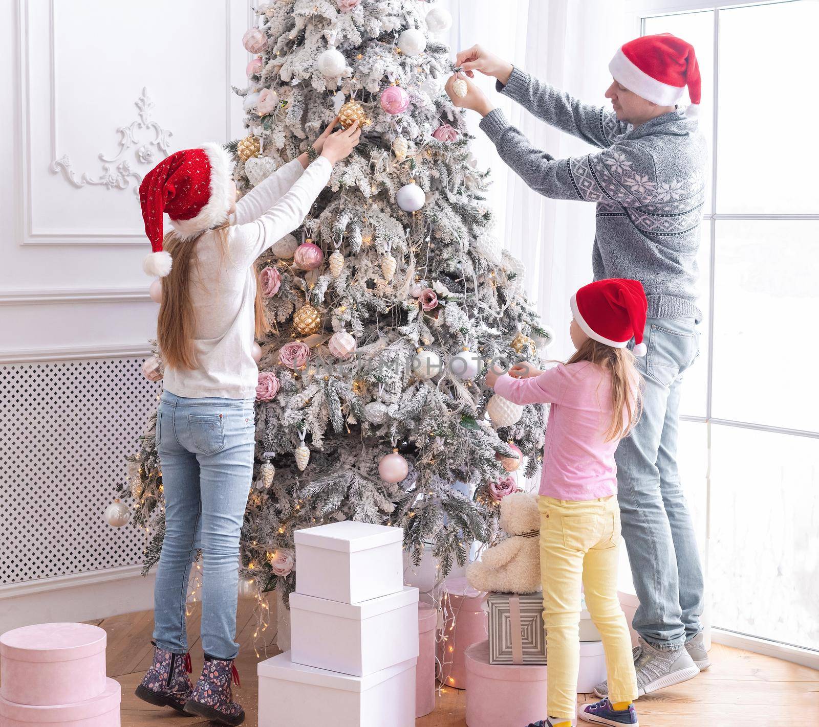 Father and daughters decorating christmas tree by tan4ikk1