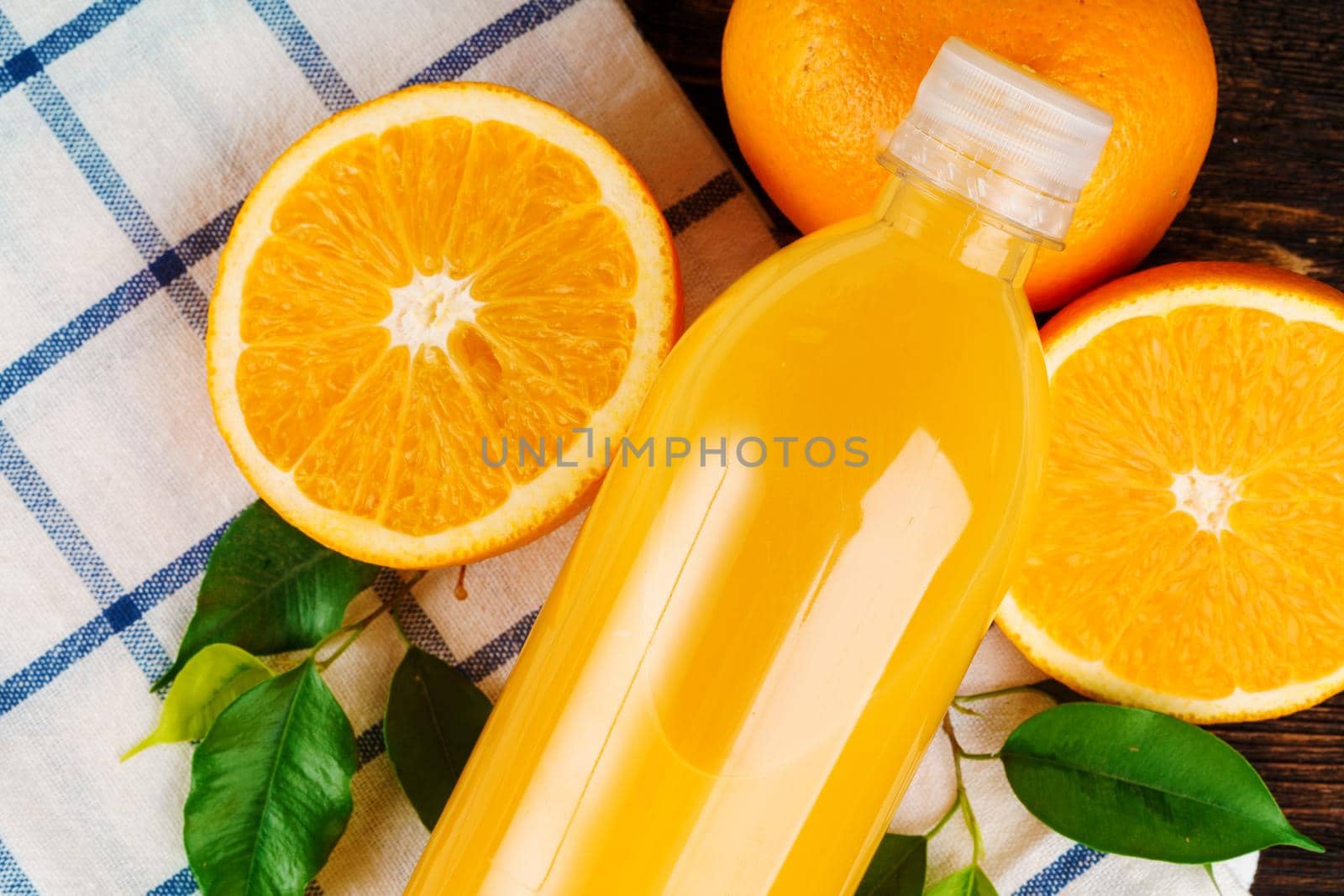 Close up of orange juice bottle with napkin on wooden table. Close up.