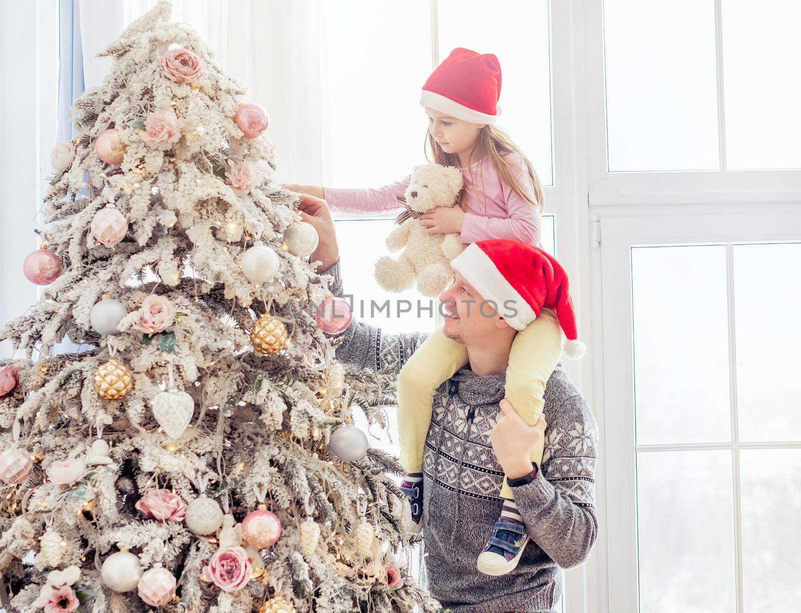 Father holding daughter near christmas tree by tan4ikk1