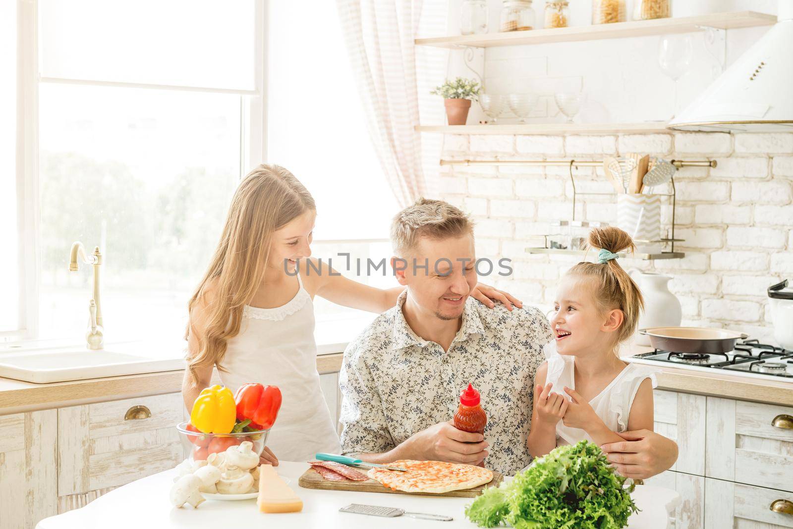 dad with two little daughters preparing pizza in the kitchen