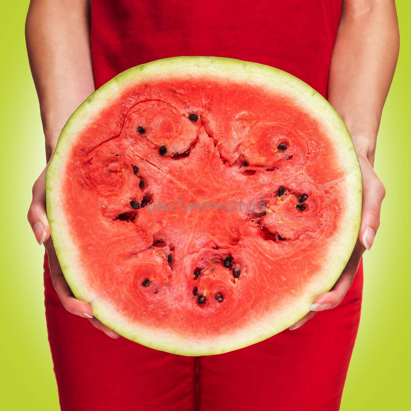 Woman holding a half of juicy watermelon on green background