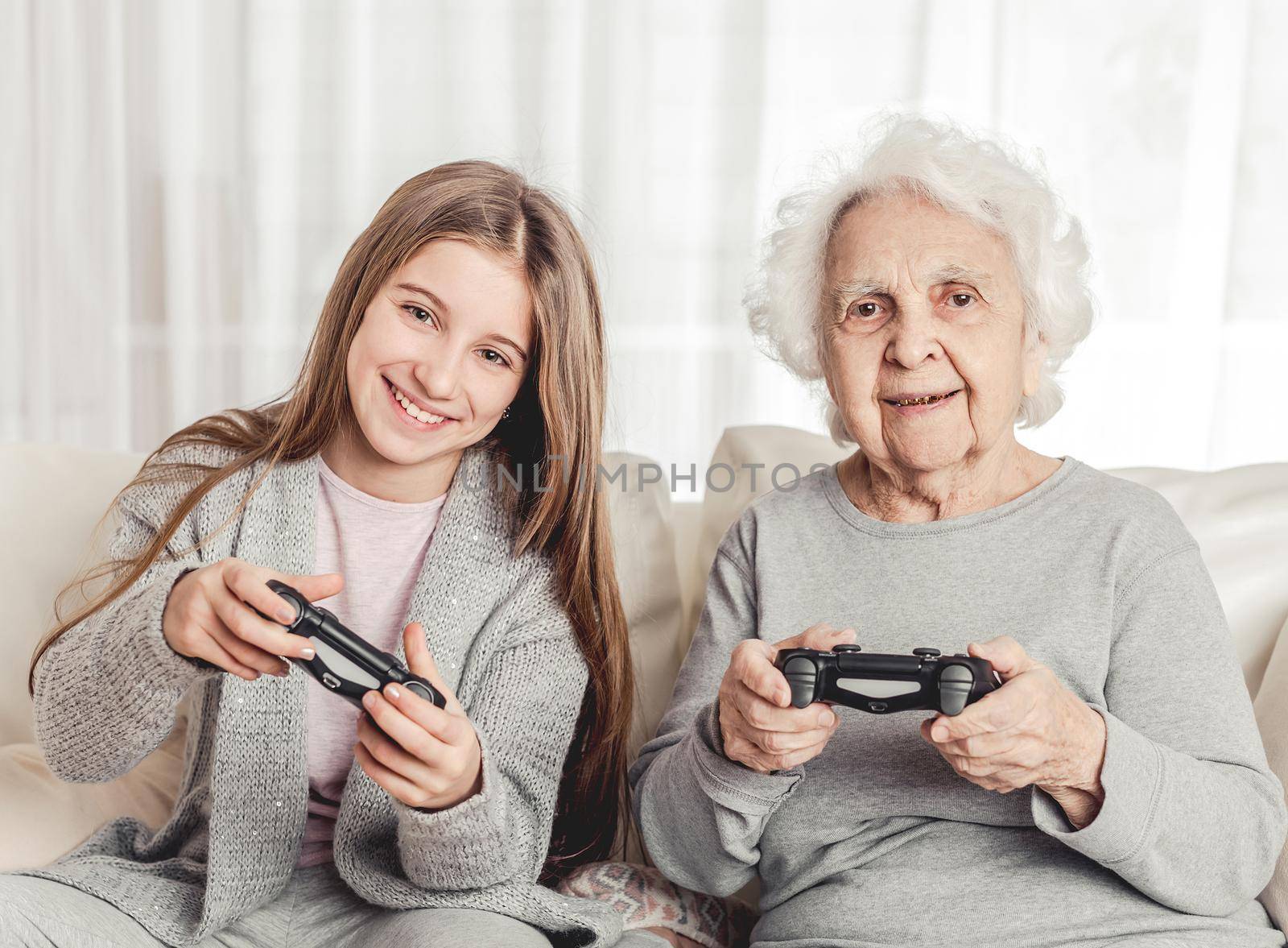 Grandmother with granddaughter playing games together with gamepads