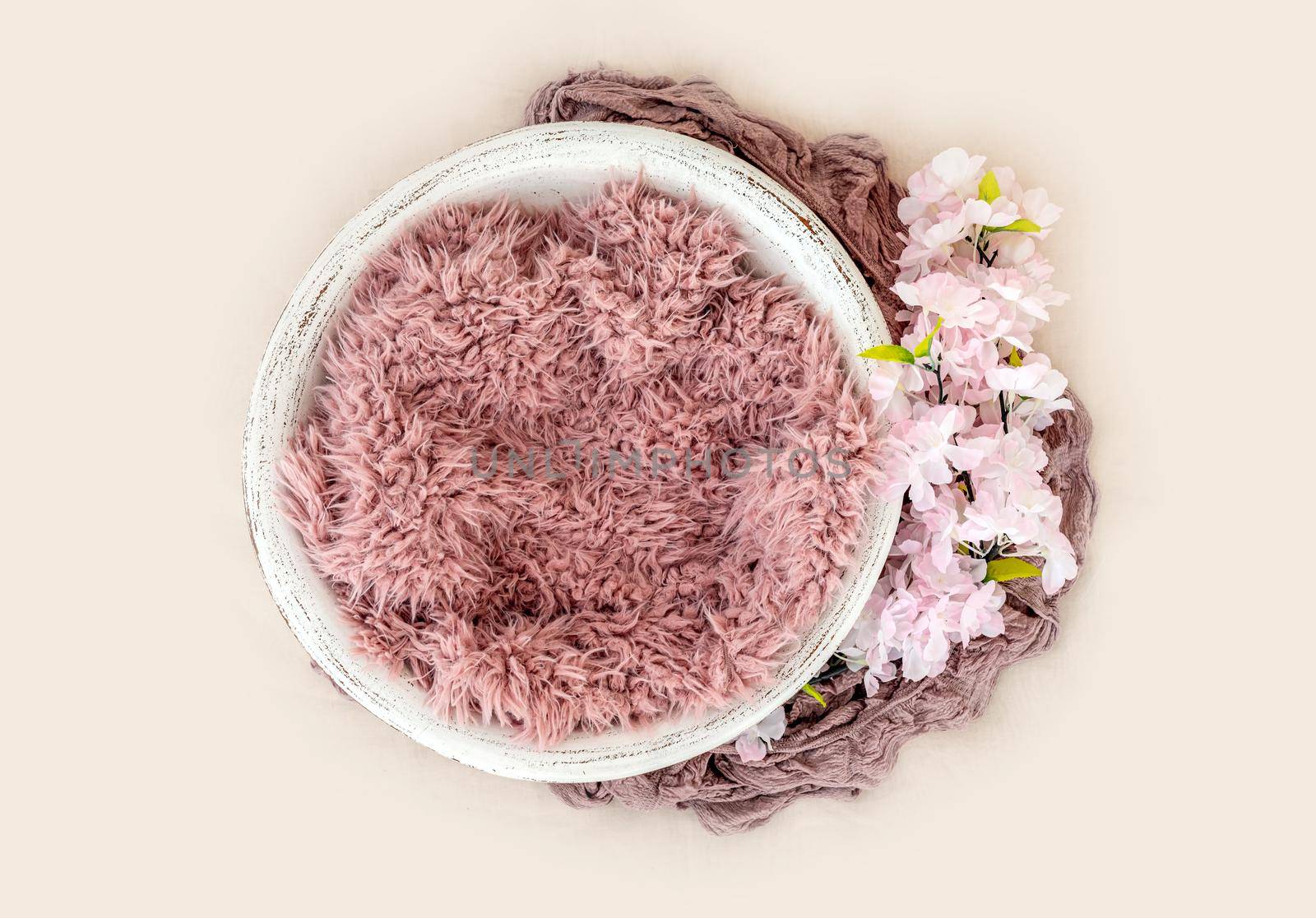 Beautiful basin furniture for newborn studio photoshoot with pink fur and white flowers decoration. Tiny designed handmade place for infant photo isolated on light background