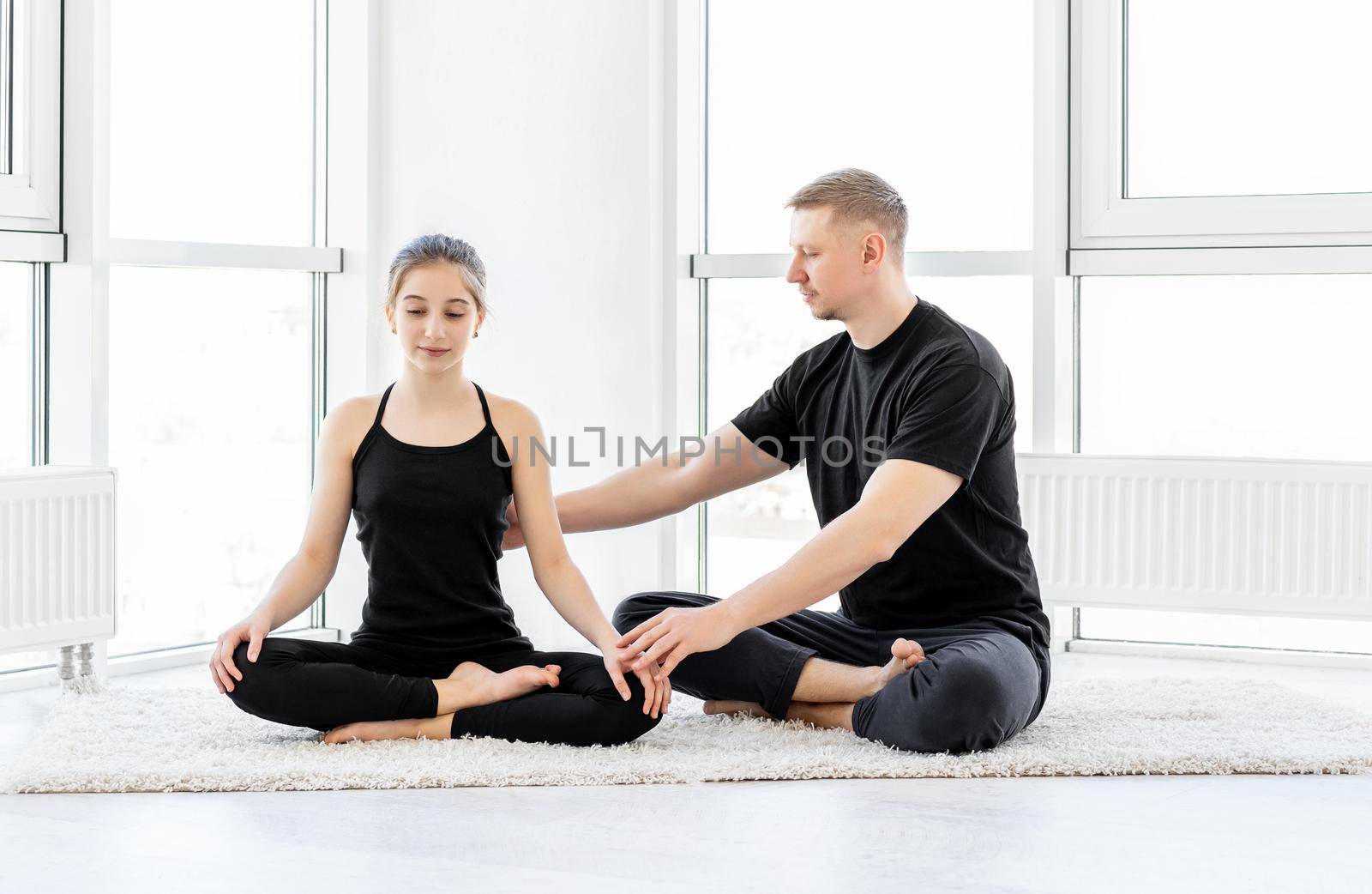 Cute girl and sporty man doing stretching workout at gym
