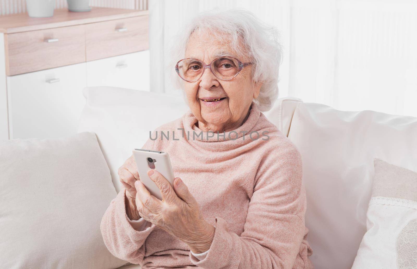 Smiling great-grandmother talking by smartphone