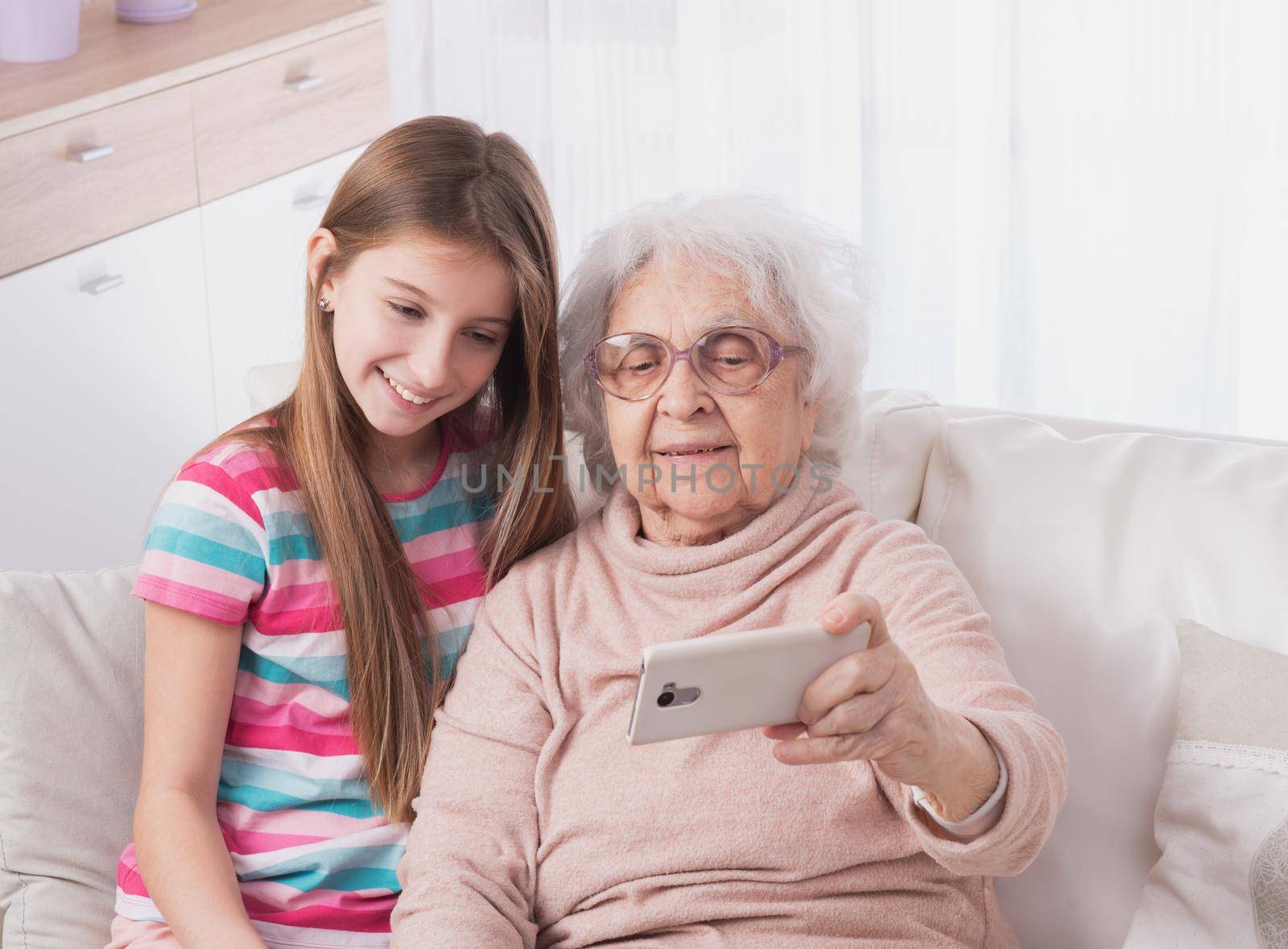Little granddaughter taking selfie with great-grandmother