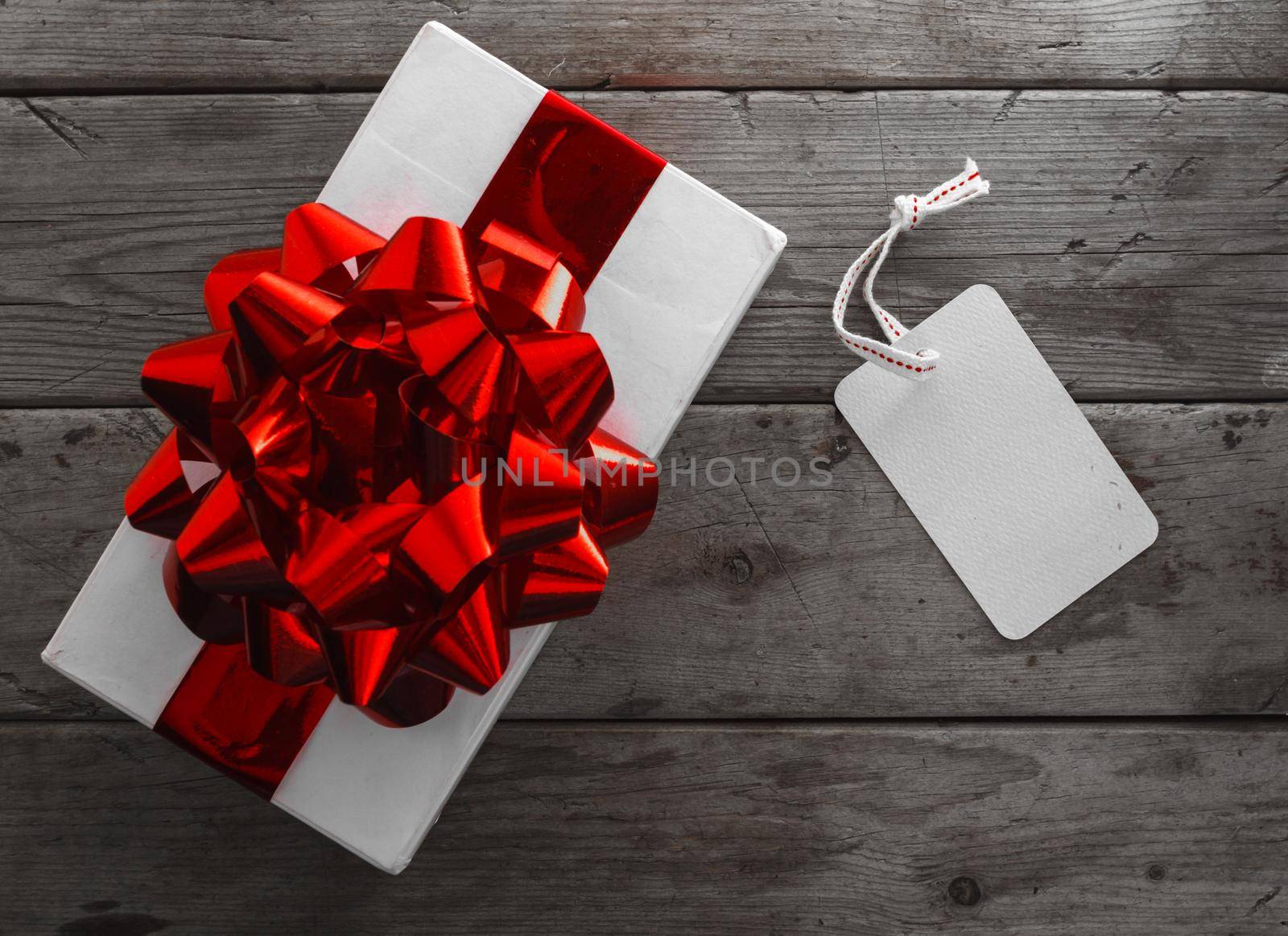 Gift box and a blank card on a wooden background, top view, space for text