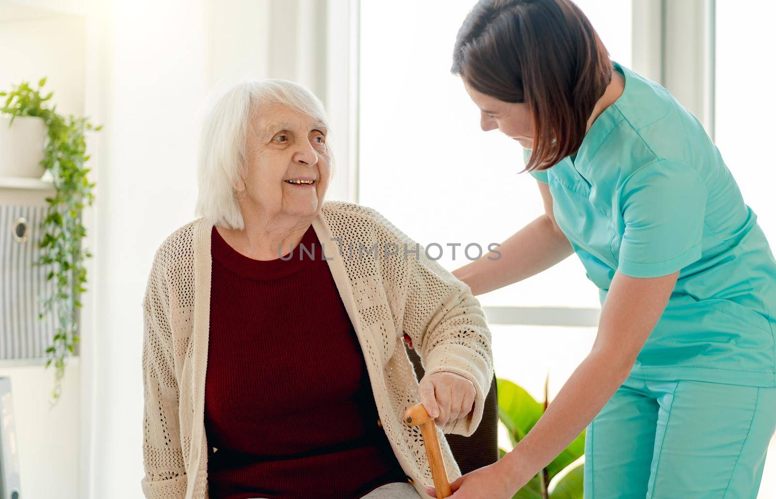 Nurse giving cane to old woman by tan4ikk1