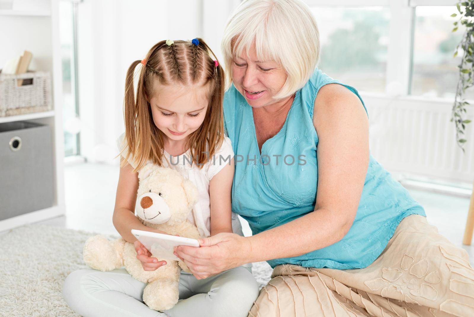 Happy grandmother with granddaughter using tablet by tan4ikk1