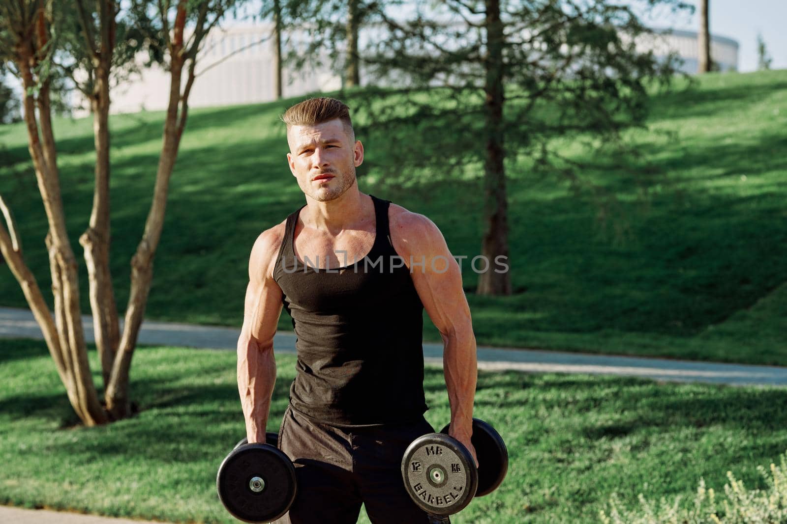 athletic man with dumbbells workout outdoors motivation. High quality photo