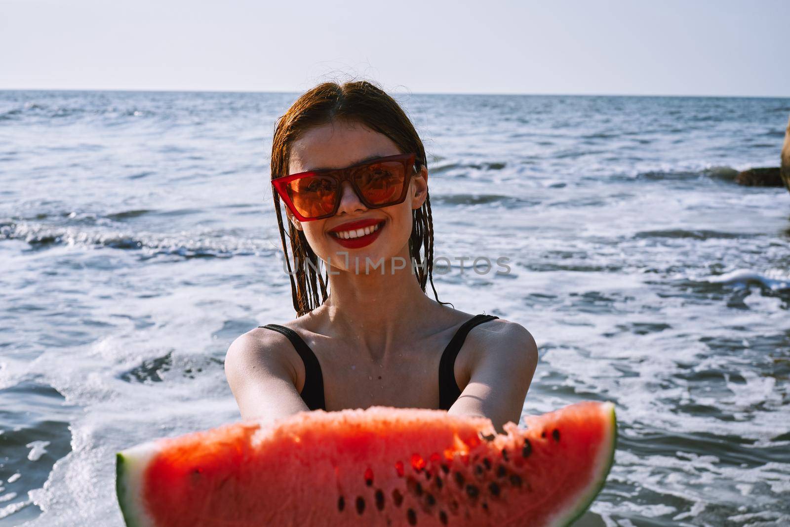 pretty woman in a black swimsuit with a watermelon in her hands summer Ocean. High quality photo
