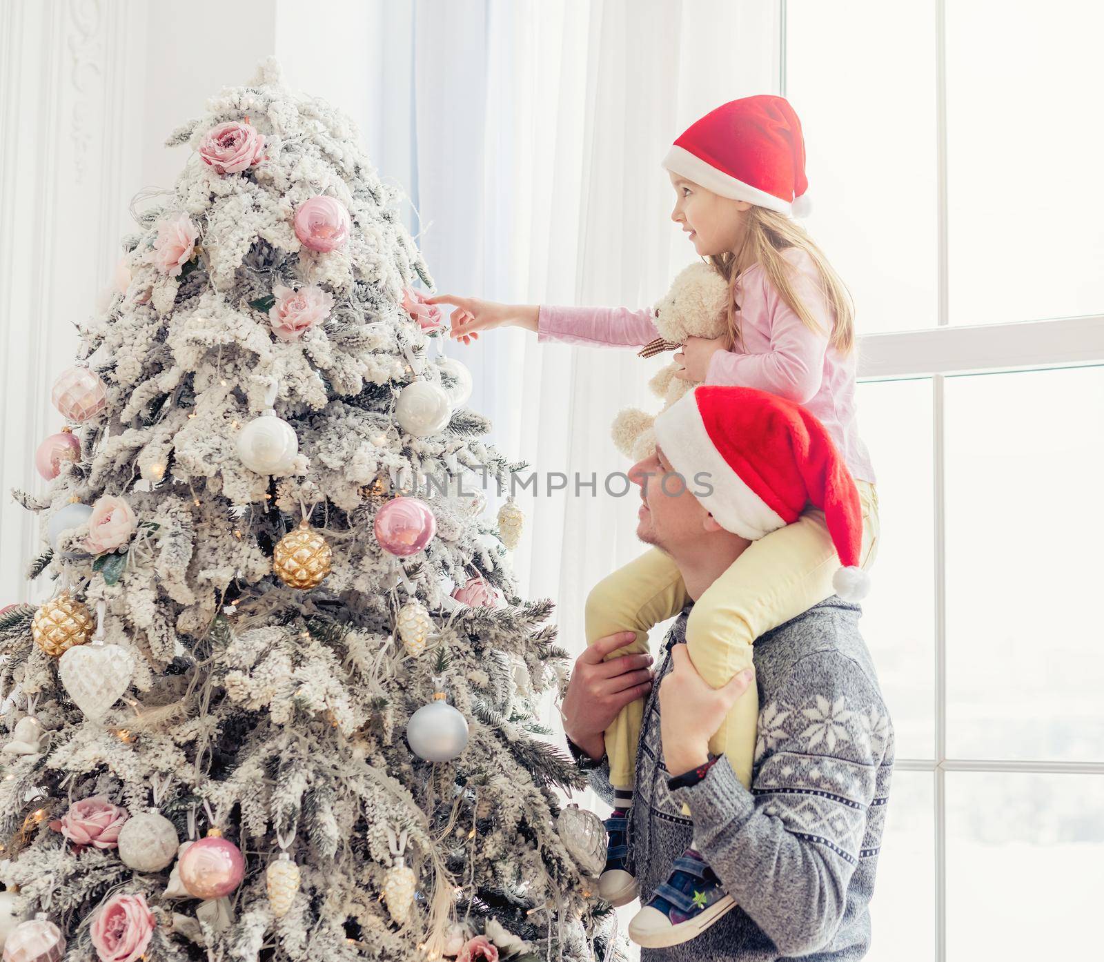 Father holding daughter near christmas tree by tan4ikk1