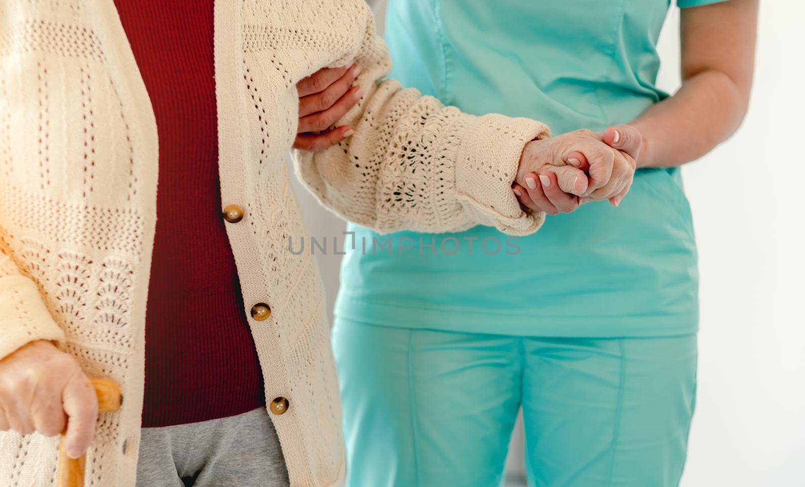 Close up view of old woman leaning on nurse while walking