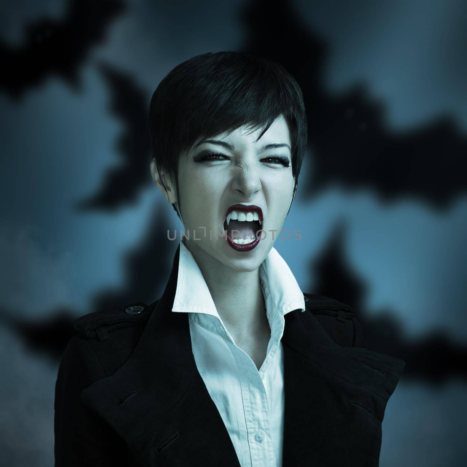 Attractive woman in the image of a vampire on a blue background with smoke