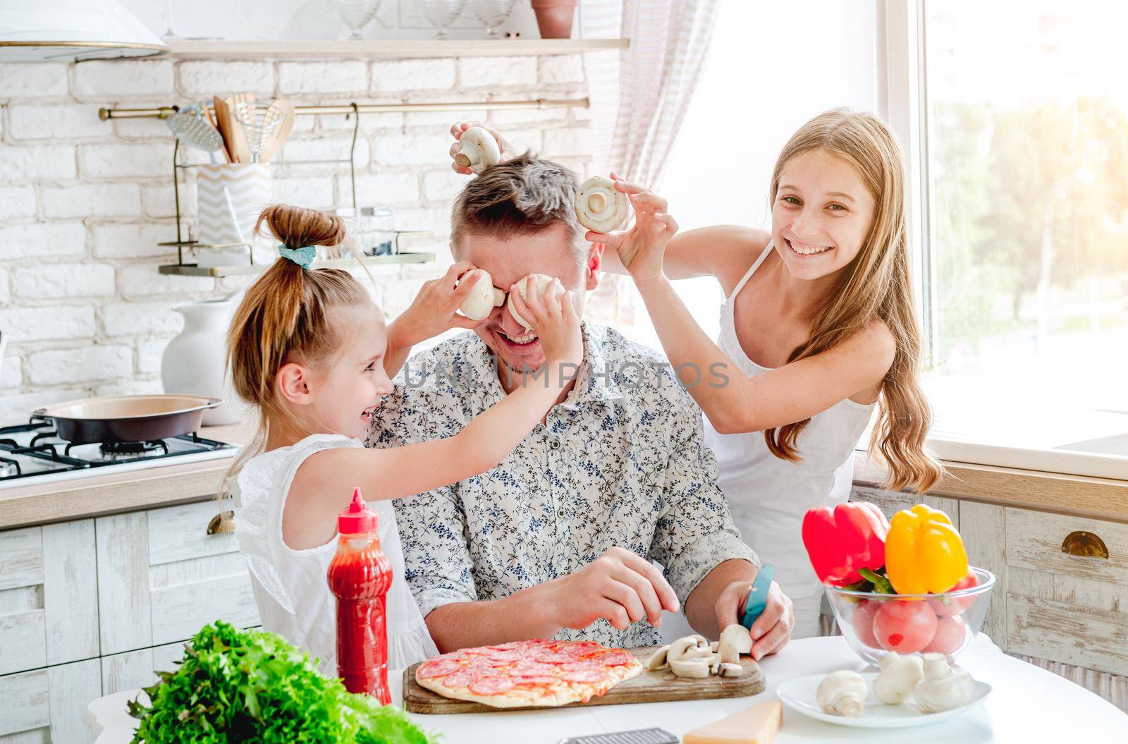 dad with two little daughters preparing pizza in the kitchen