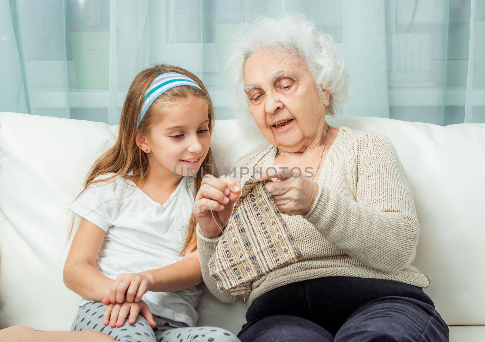 ganddaughter learning to embroider with granny on sofa