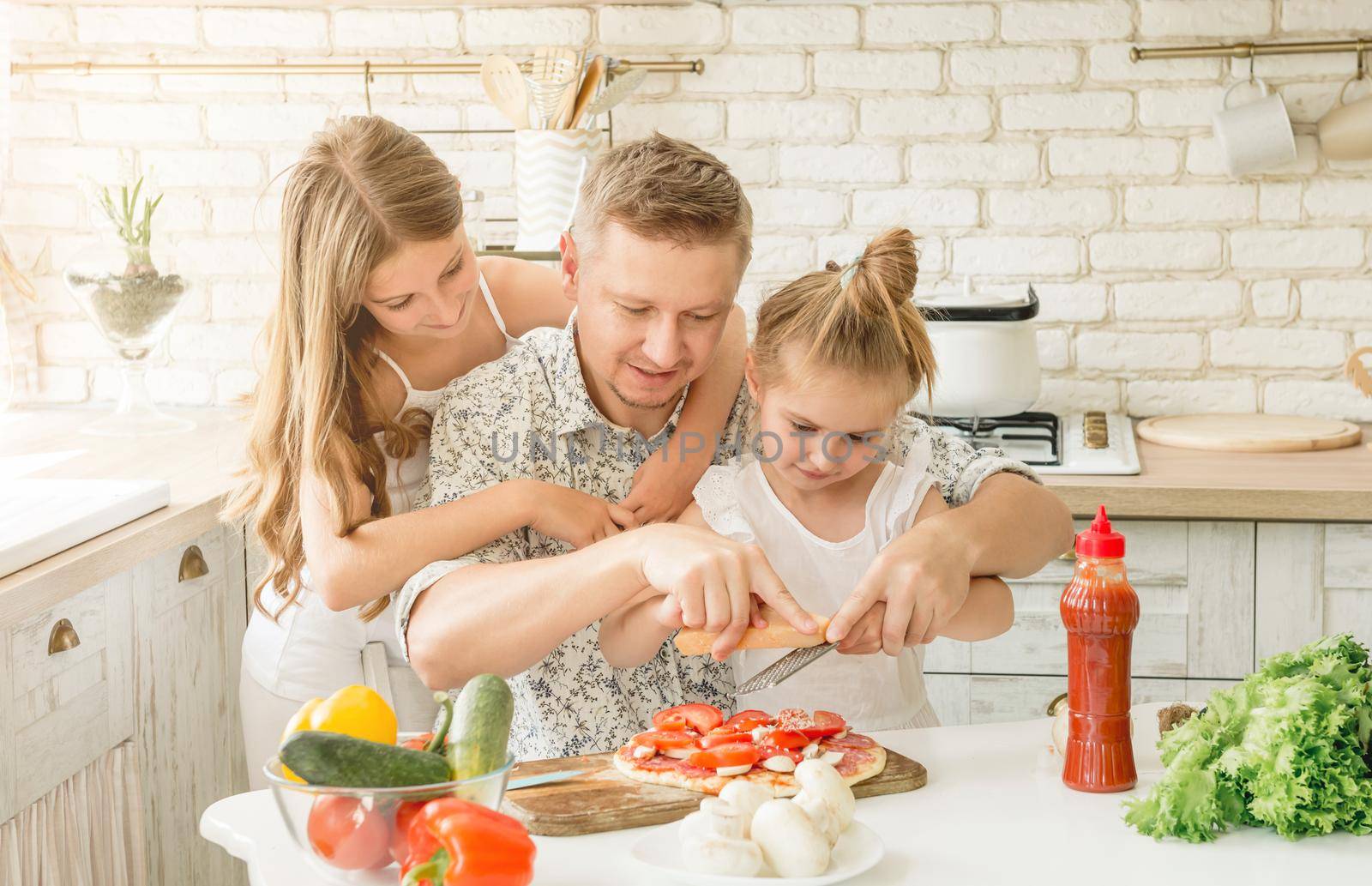 dad with two little daughters preparing pizza in the kitchen