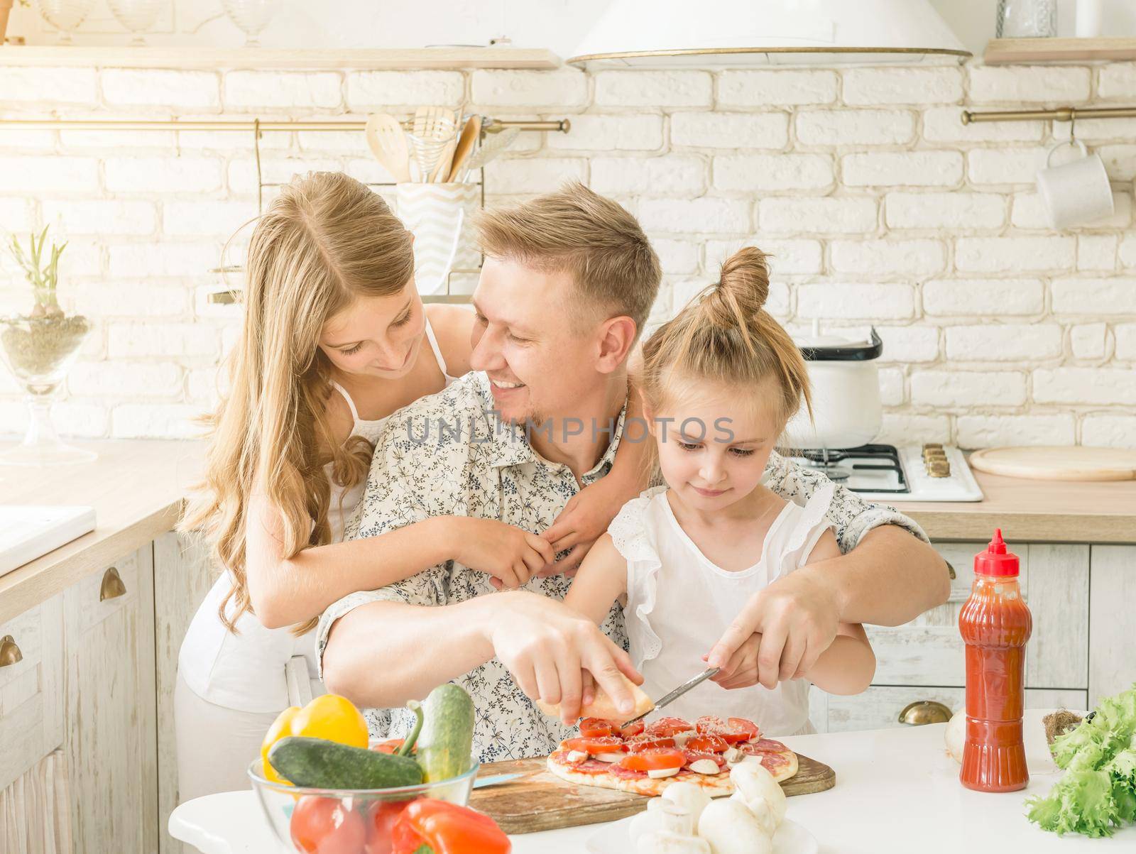 dad with two little daughters preparing pizza in the kitchen