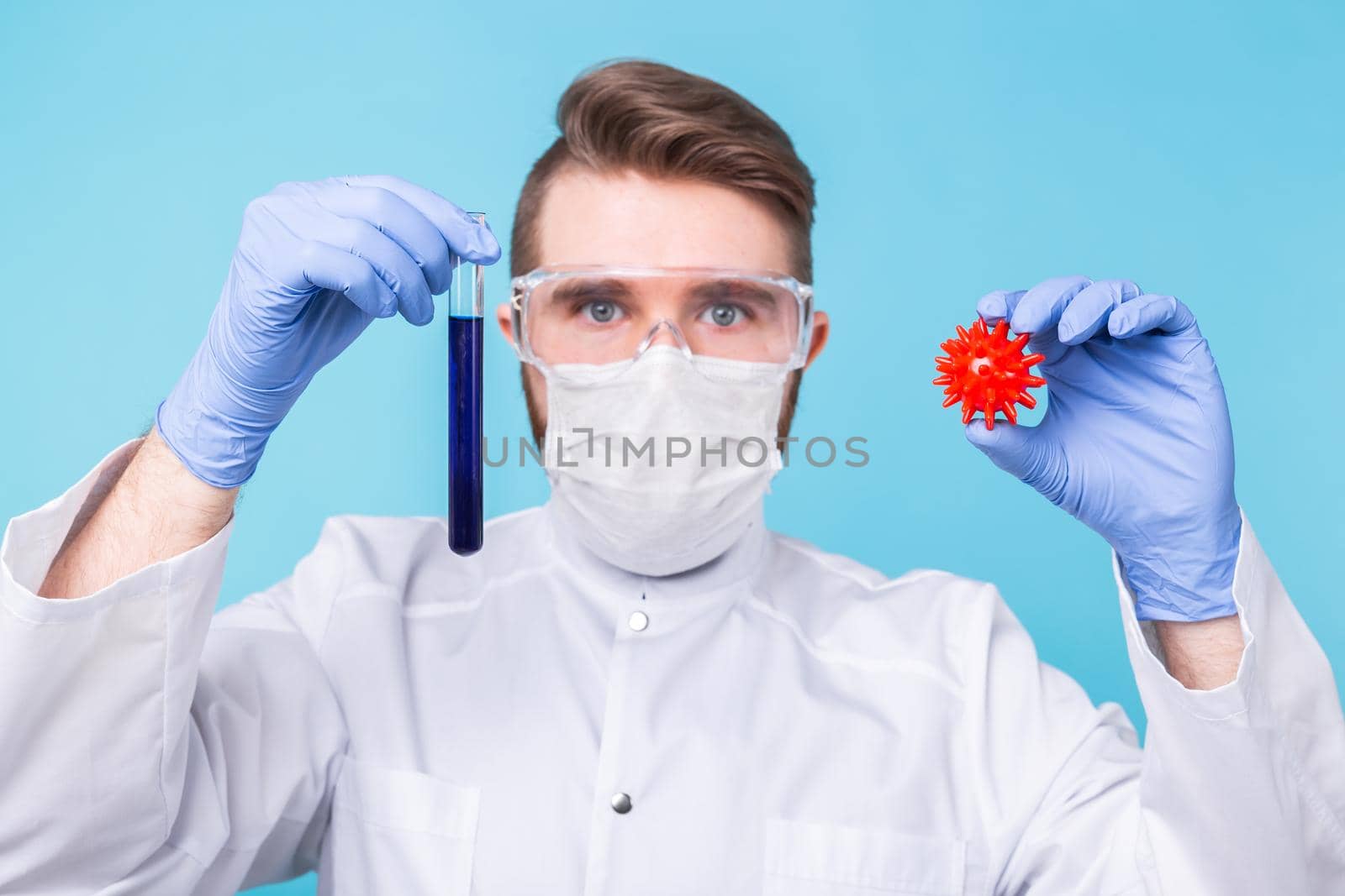 Covid-19, Vaccine development, pandemic, outbreak and medicine concept - Man scientist in flu mask and protective gloves holding a model of coronavirus and test tube. by Satura86