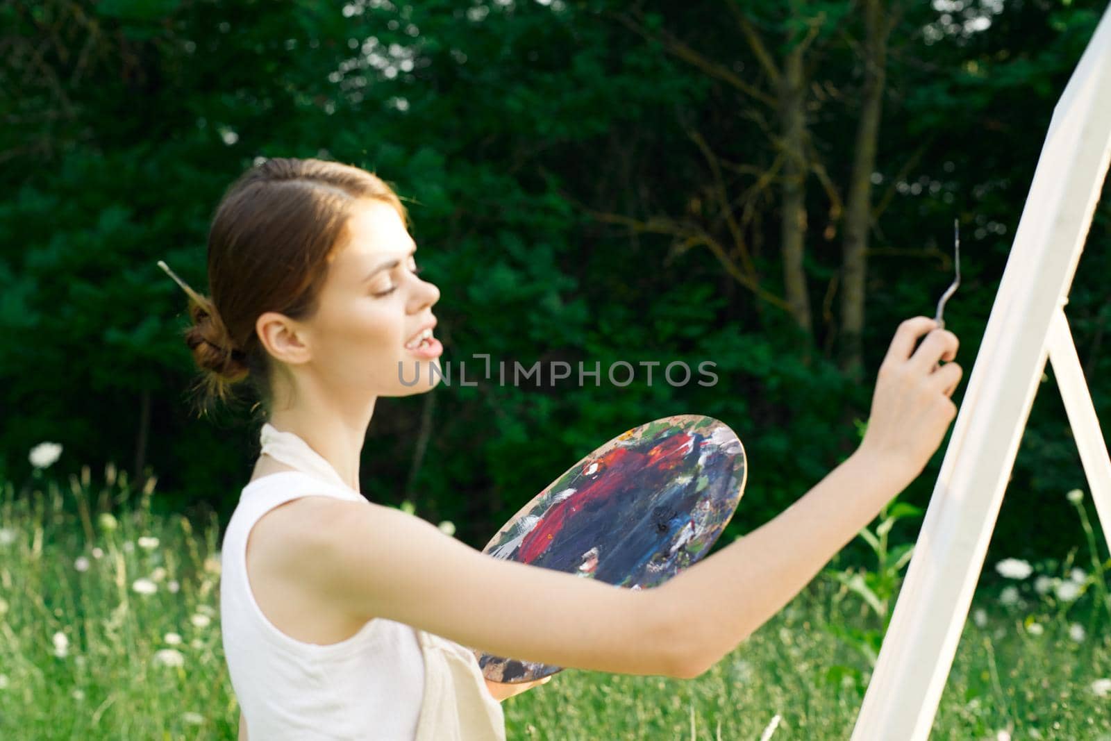 woman artist outdoors with palette of paints paints a picture by Vichizh