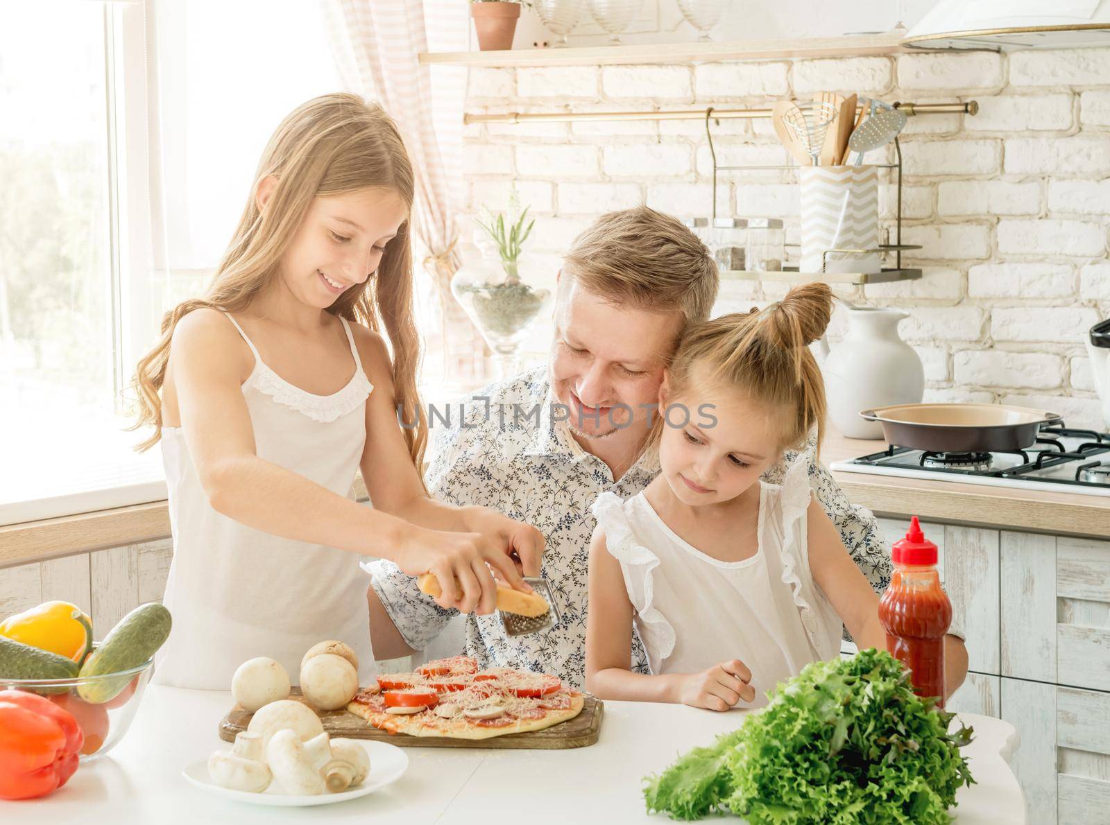 dad with two little daughters preparing pizza in the kitchen