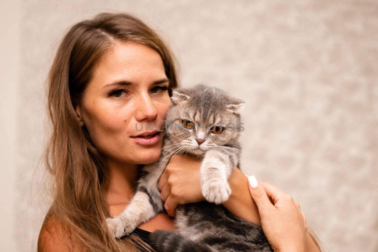 Attractive girl embracing her pet with smile. Indoor portrait of cute ginger woman playing with cat.