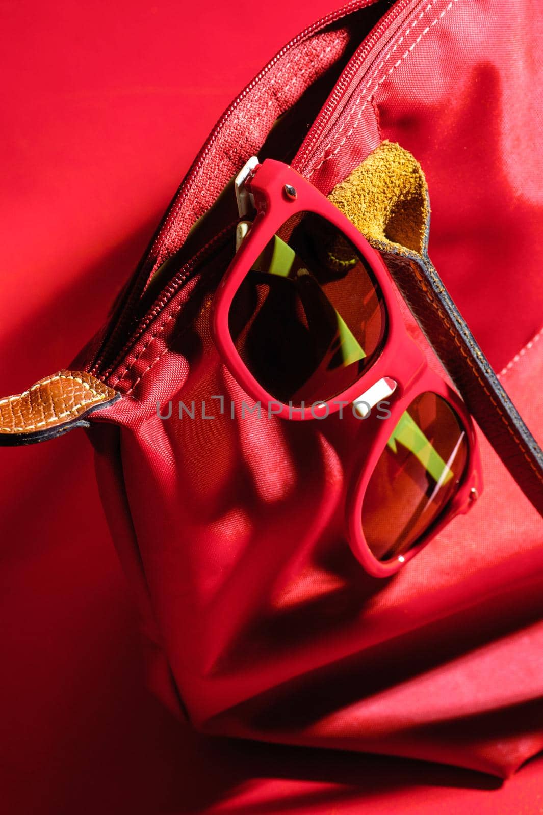 woman accessory, closeup red plastic sunglasses over red background