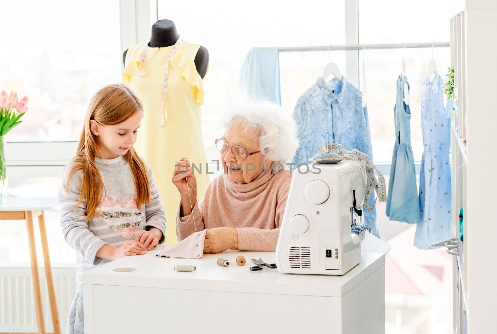 Granny sewing with granddaughter in light workshop
