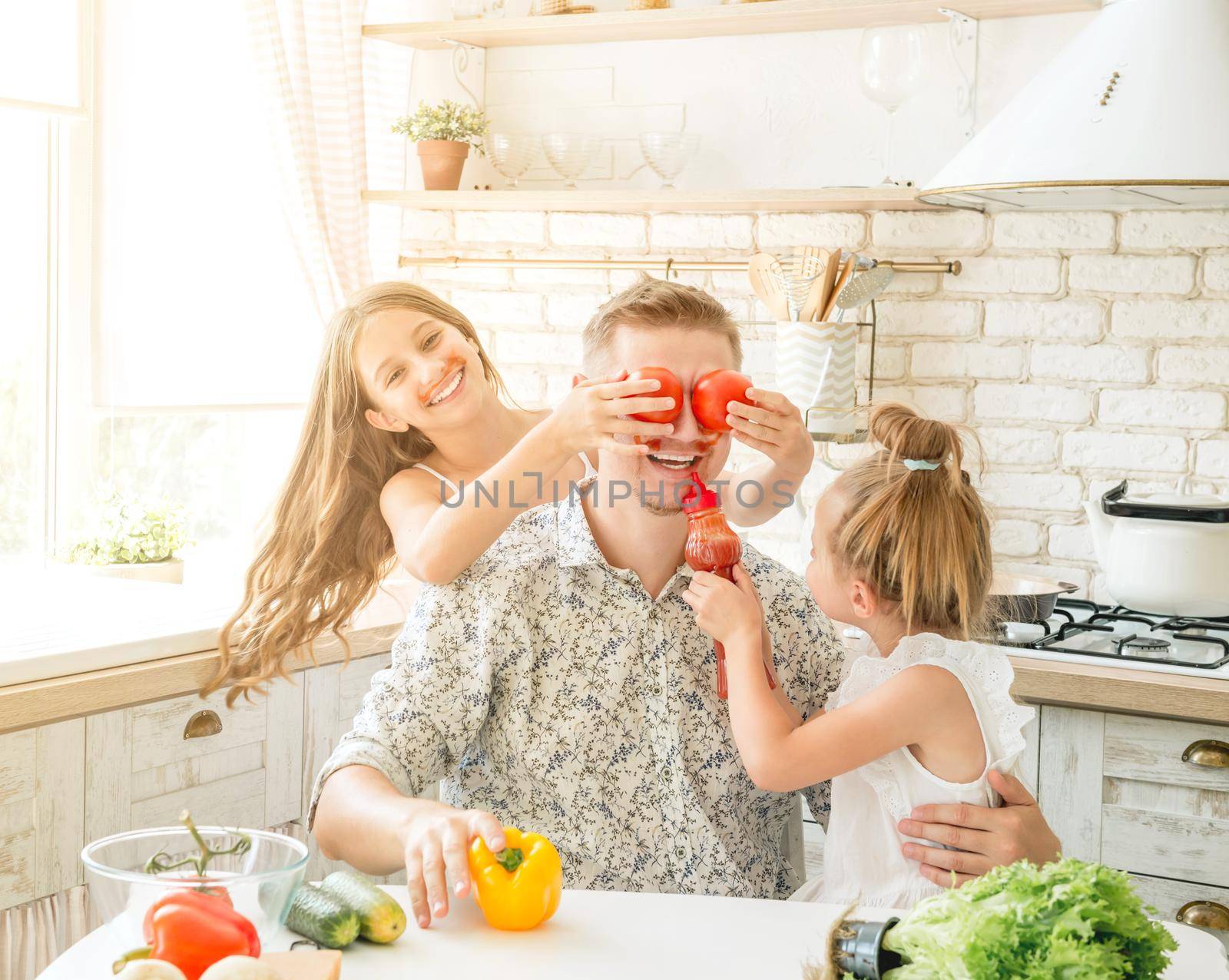 dad with two little daughters have a fun in the kitchen