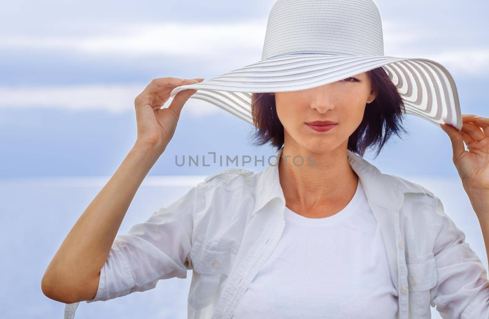 Fashionable woman in a hat on a background of the sea