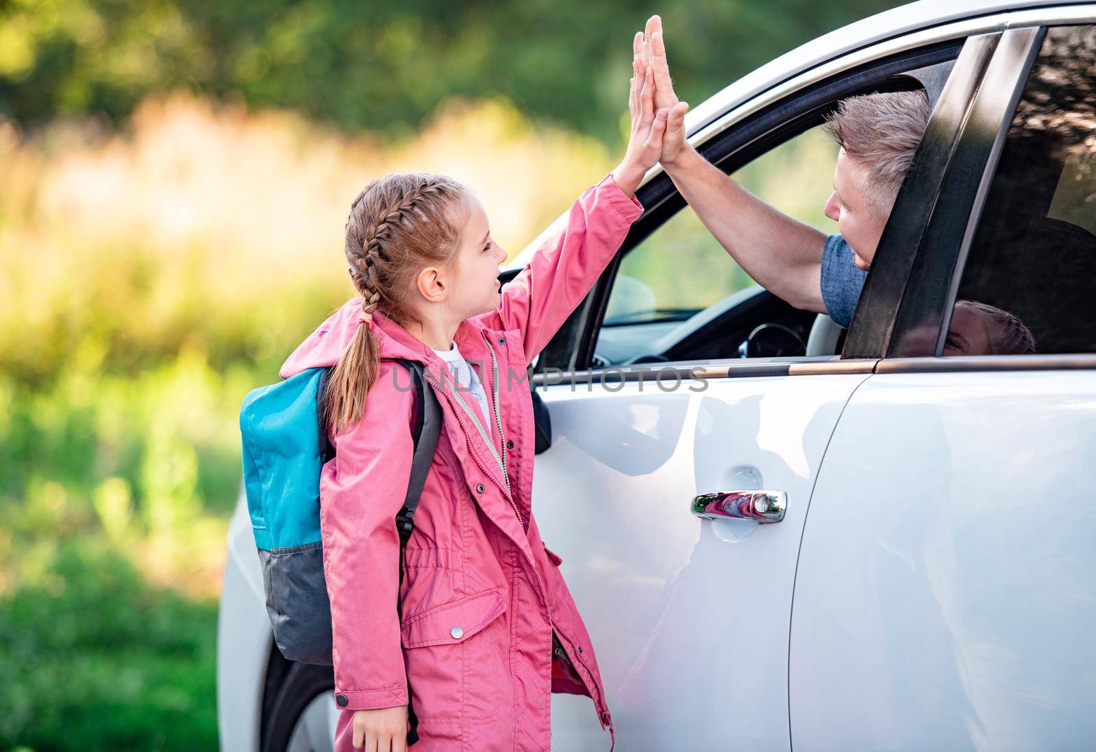 Girl schooler giving five to father sitting in car