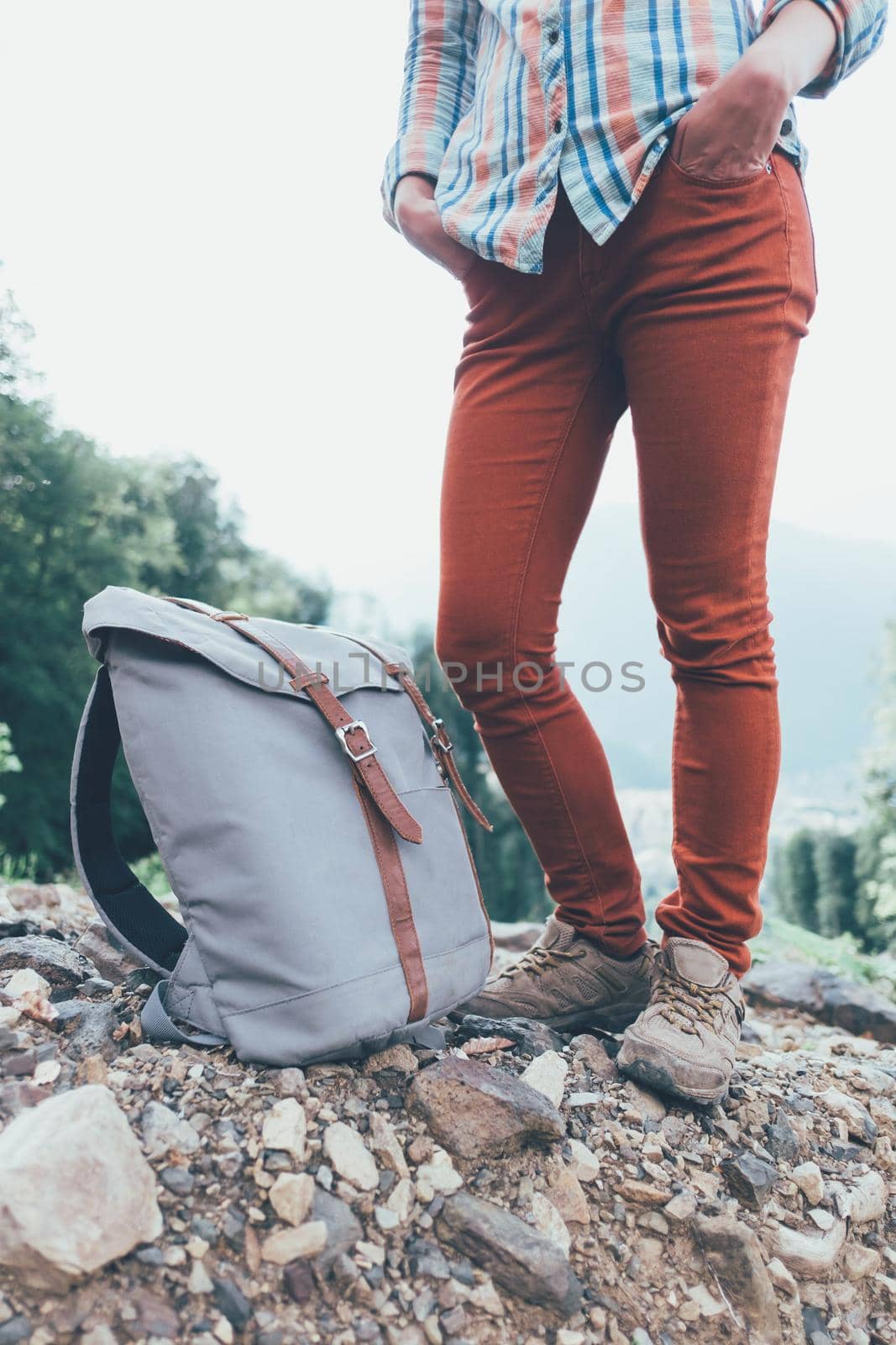 Unrecognizable female traveler standing with backpack outdoor, view of legs.