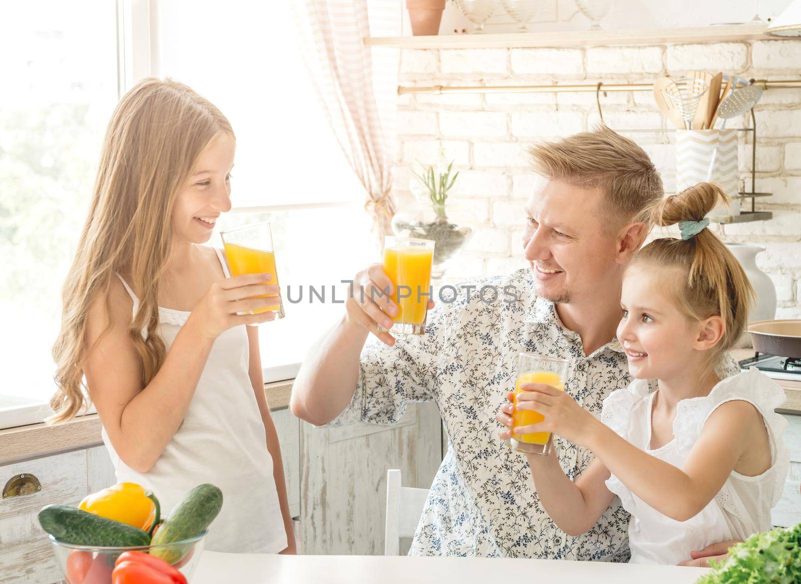 Dad with two daughters drinks juice by tan4ikk1