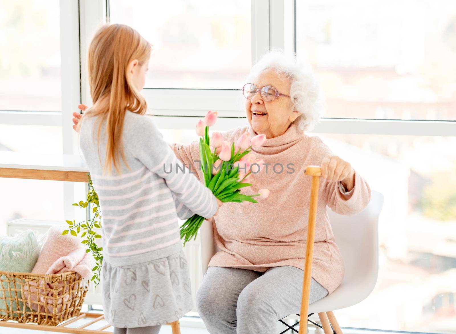 Girl presenting bouquet to old woman by tan4ikk1