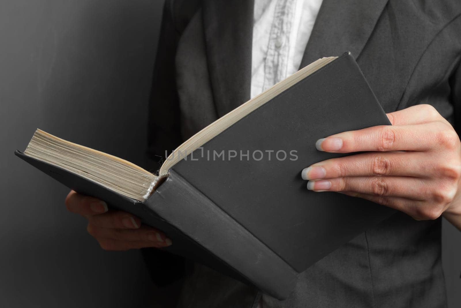 Unrecognizable woman reading a book near blackboard, close-up