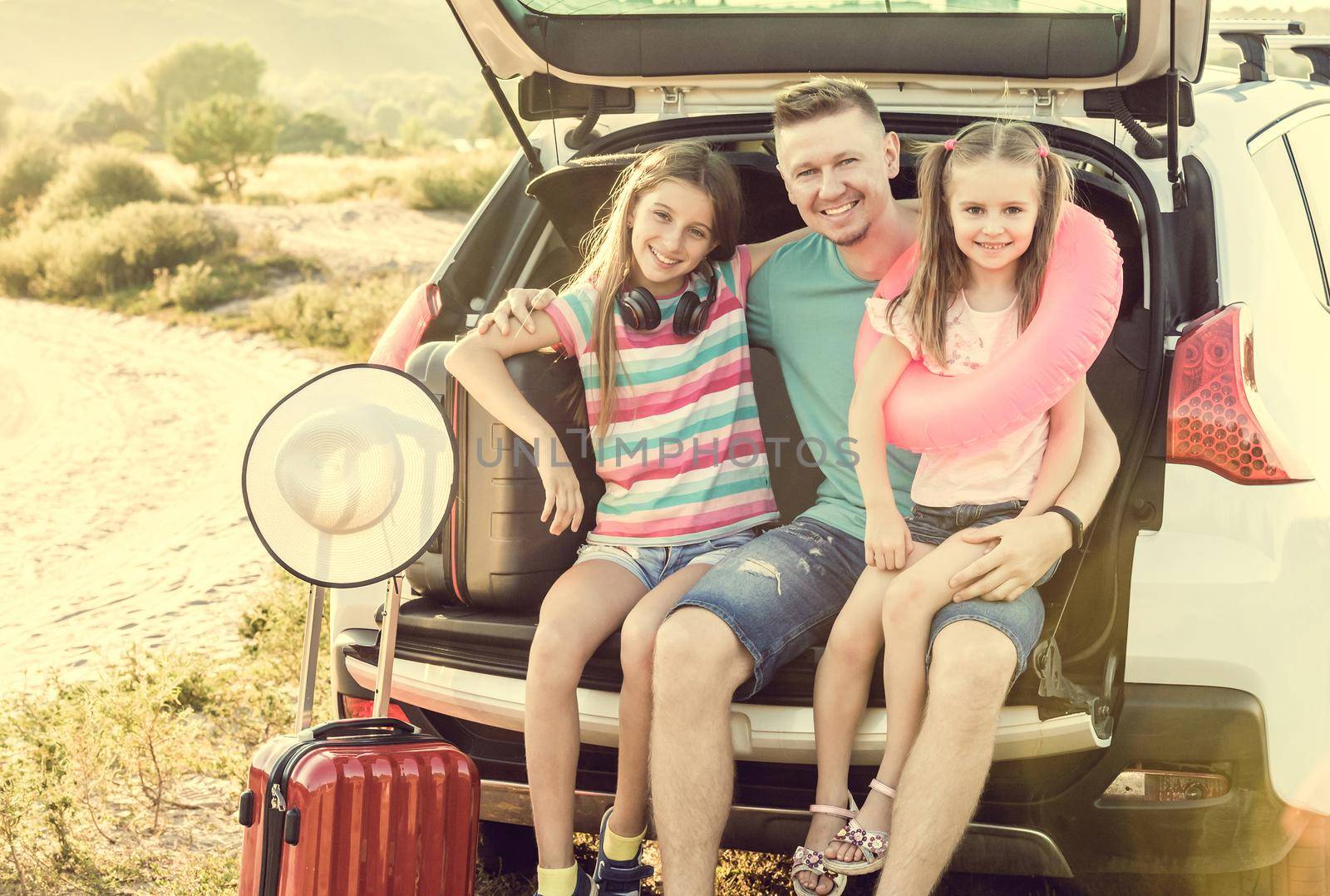 Little cute girl in the trunk of a car with suitcases by tan4ikk1