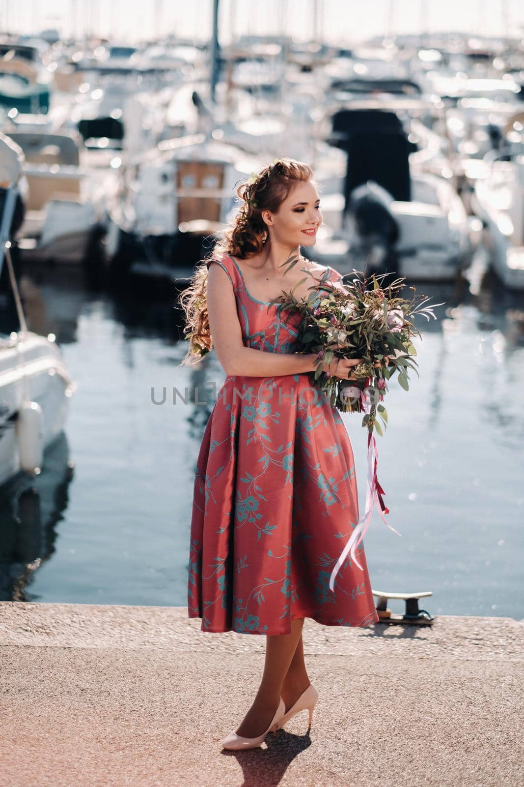 Young model girl in a beautiful dress with a bouquet of flowers on the beach in France. Girl with flowers in spring Provence on the French Riviera.