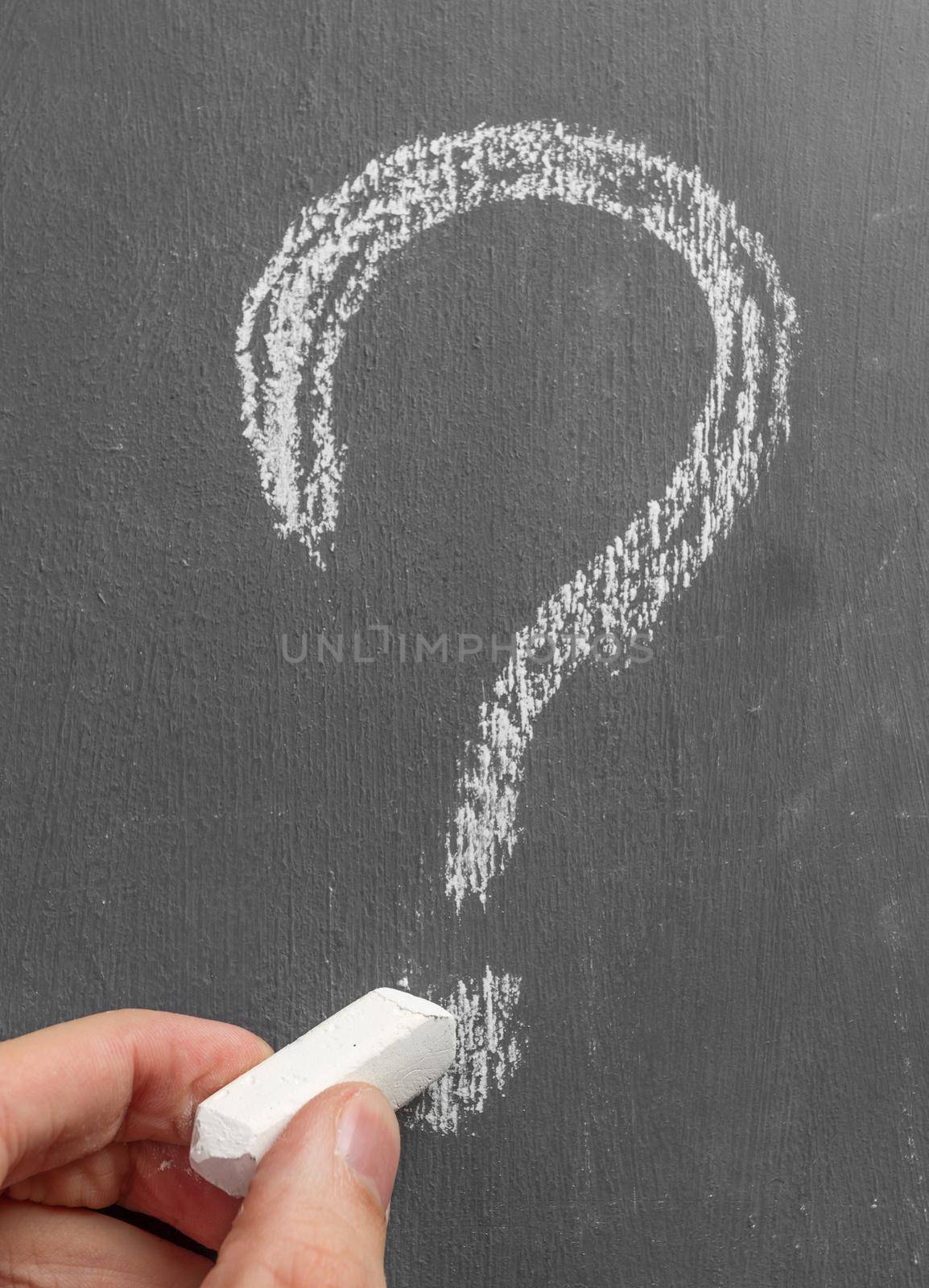 Person writes by chalk on the blackboard question mark
