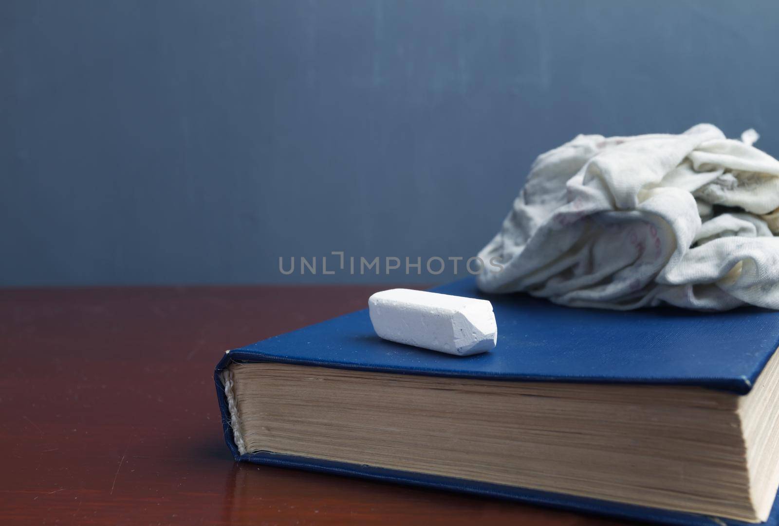 There are book, chalk on the table against the blackboard